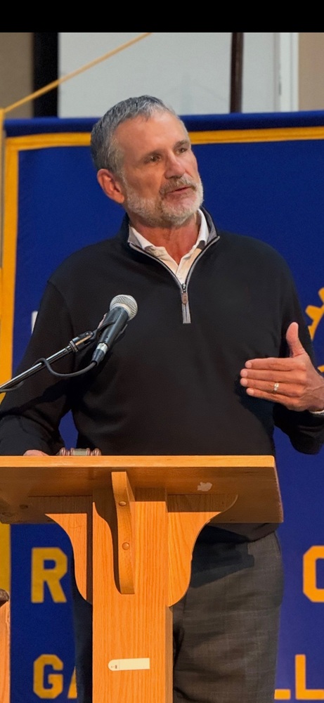 Bob Norton standing at a podium, engaged and speaking with the community.